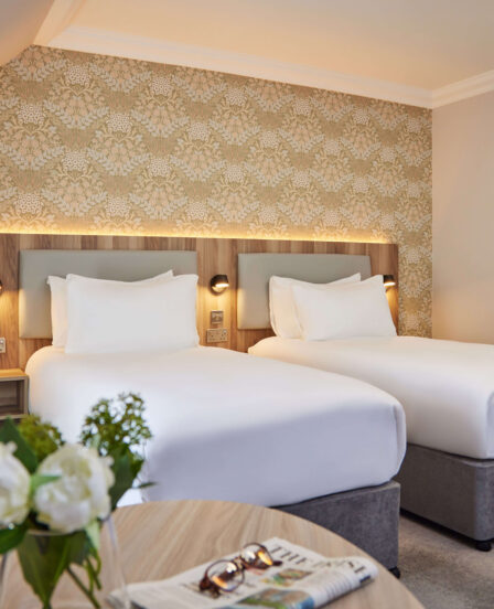Elegant twin room with cosy beds, stylish decor, coffee station, and soft lighting; perfect for a comfortable stay.