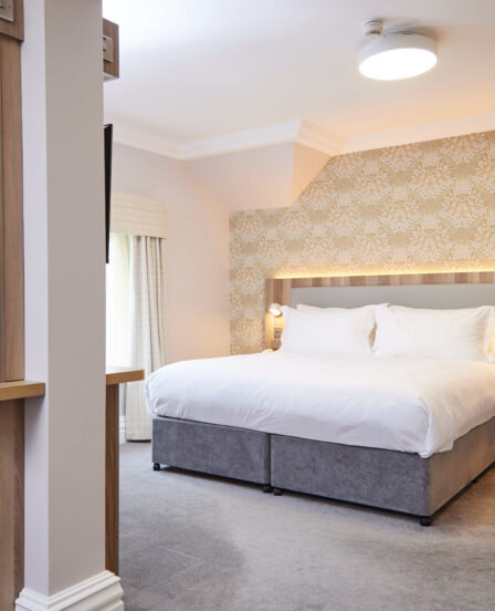 Spacious luxury hotel room with king bed, modern decor, flat-screen TV, and tea facilities, ensuring a relaxing stay.