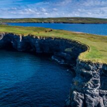 Stunning cliff views over azure sea with lush green fields, perfect for serene nature walks near holiday accommodation.