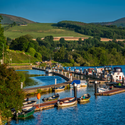 Charming lakeside view with boats and lush green hills at peaceful countryside hotel marina.