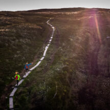 Guests walking on scenic hillside trail at sunset, enjoying stunning panoramic views and vibrant landscapes.