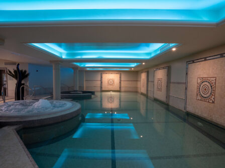 Elegant indoor pool and jacuzzi with mosaic tiles and soft lighting.