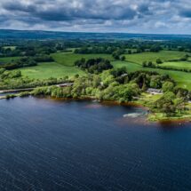 Scenic lakeside view with lush green landscape and distant countryside, perfect for a tranquil stay surrounded by nature.