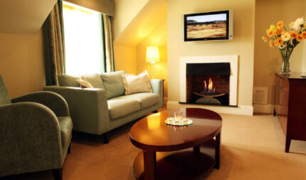 Inviting hotel lounge with cosy sofa, warm fireplace, soft lighting, and stylish decor. Ideal for relaxation and comfort.
