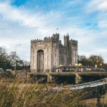 Scenic view of a historic castle by a riverside, offering guests a serene escape with beautiful architecture and lush surroundings.