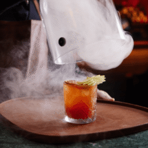 Luxurious cocktail with apple garnish and smoke at elegant hotel bar.