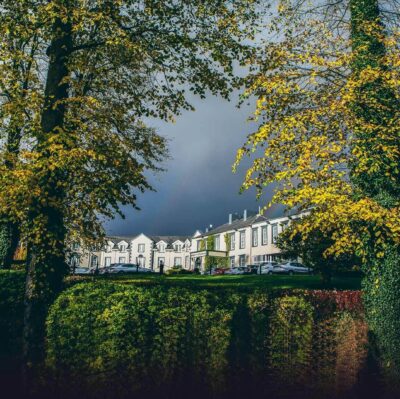 Elegant hotel with classic architecture nestled among lush trees, offering tranquillity and premium amenities for a relaxing stay.