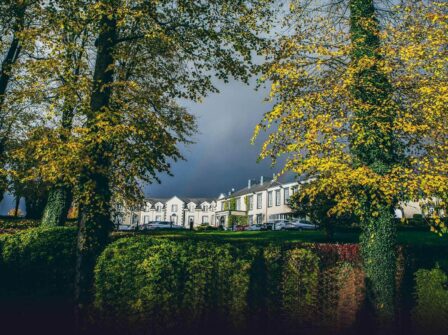 Elegant hotel with classic architecture nestled among lush trees, offering tranquillity and premium amenities for a relaxing stay.