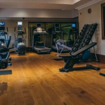 Modern hotel gym with treadmills, exercise bikes, and weight machines on wooden flooring, inviting fitness enthusiasts.