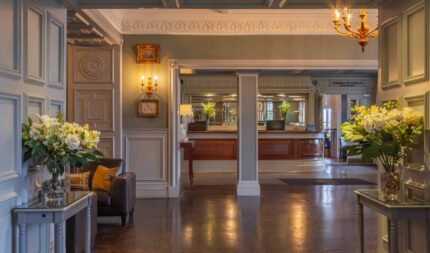 Elegant hotel lobby with plush seating, fresh flower arrangements, grand chandelier, and welcoming reception desk.