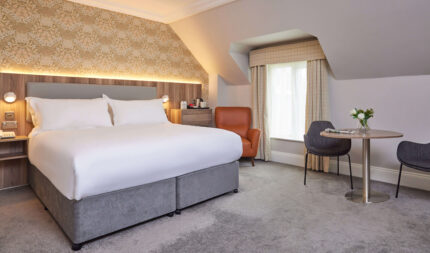 Executive double room with super-king bed, modern neutral décor, separate living area, workspace, smart TV, and luxury bathroom with rainfall shower