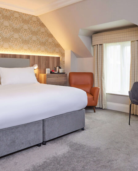 Executive double room with super-king bed, modern neutral décor, separate living area, workspace, smart TV, and luxury bathroom with rainfall shower