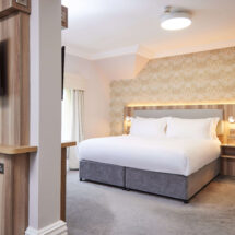 Spacious hotel room with cosy king bed, stylish décor, flat-screen TV, and coffee facilities, perfect for relaxation.
