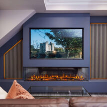Modern hotel suite lounge with cosy fireplace, plush cushions, large TV displaying scenic view, designed for relaxation.