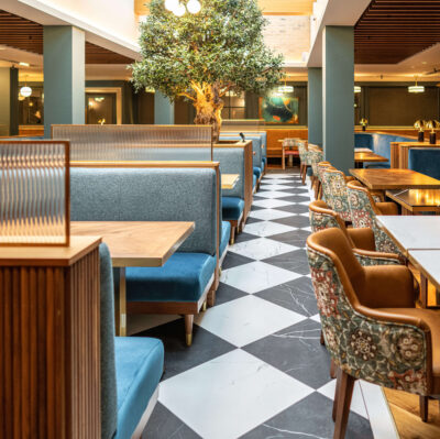 Stylish hotel dining area with plush seating, skylight, and indoor tree, offering a modern and inviting atmosphere.