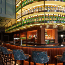 Elegant hotel bar with curved shelves, plush seating, ambient lighting, ideal for relaxing evenings and social gatherings.
