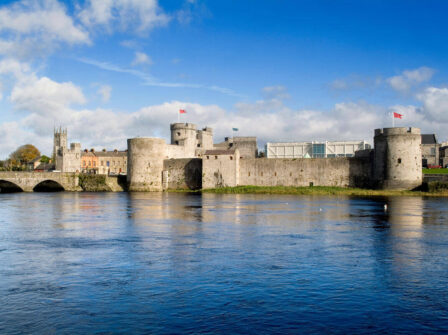 Riverside view of historic castle, vibrant sky, and lush grounds offering an elegant, cultural retreat near city centre.