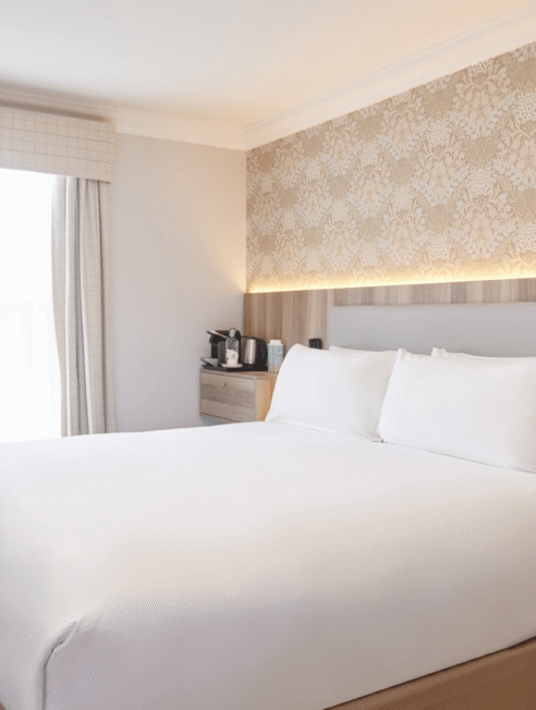 Elegant hotel room with plush bed, stylish wallpaper, and modern amenities for a comfortable stay.