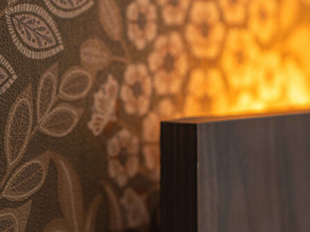 Cosy hotel room corner with elegant floral wallpaper and warm ambient lighting.