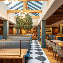 Bright, modern hotel dining area with skylight, colourful mural, elegant chairs, and inviting atmosphere.