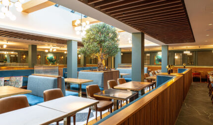 Contemporary hotel dining area with cosy booths, natural light, stylish decor, perfect for guests to enjoy breakfast.