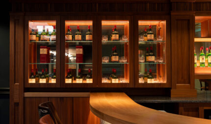 Elegant hotel bar with a warm wooden counter, stocked with premium spirits, inviting seating, and ambient lighting.