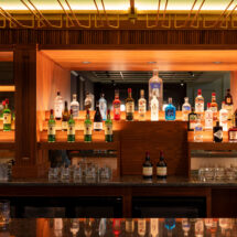 Elegant hotel bar with illuminated liquor display, showcasing premium spirits and inviting atmosphere for relaxation.