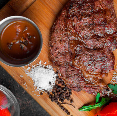 Savour premium steak with rich sauce, fresh tomatoes, and seasoning on wooden board at luxury hotel restaurant.