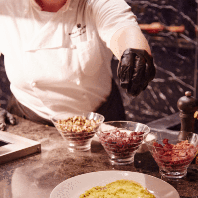 Chef preparing gourmet omelette at live cooking station with toppings in luxurious hotel restaurant.