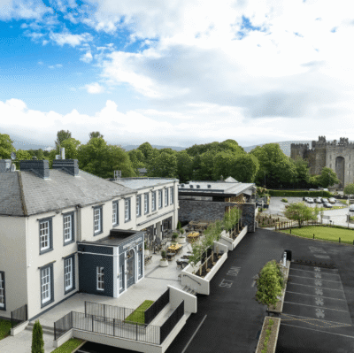 Charming countryside hotel with historic castle views, lush greenery, and inviting outdoor terrace for a relaxing stay.