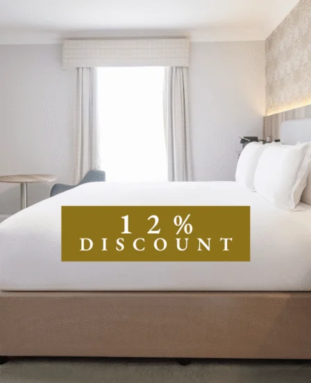 Spacious hotel room with plush king bed, modern decor, flat-screen TV, and elegant wallpaper. Enjoy luxury and comfort.