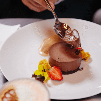 Delectable chocolate dessert with strawberries, ice cream, and edible flowers at luxurious hotel restaurant.