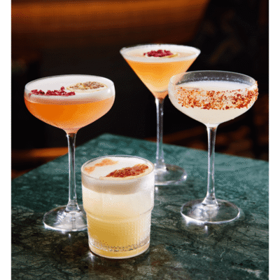 Elegant cocktails on green marble, with vibrant garnishes; an inviting hotel bar experience.