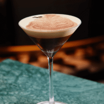 Elegant espresso martini on marble bar with comforting ambience.