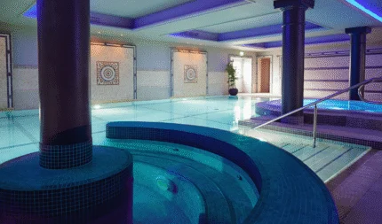 Luxurious hotel spa with tranquil pool, jacuzzi, elegant mosaic decor, and soothing lighting for relaxation.