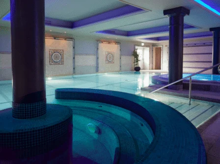 Luxurious indoor pool with modern decor and inviting jacuzzi, perfect for relaxation at a premium hotel spa retreat.
