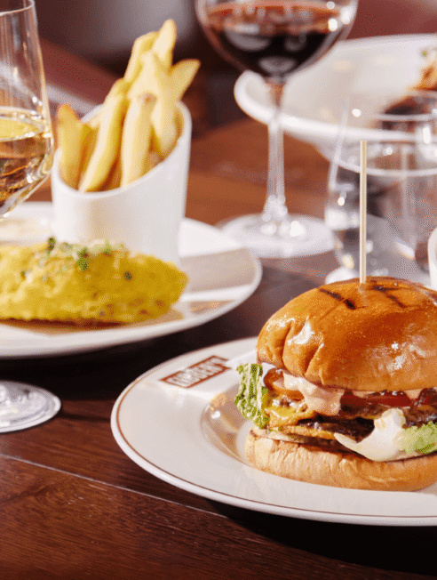 Gourmet burger and chips with wine in elegant restaurant, showcasing fine dining experience.