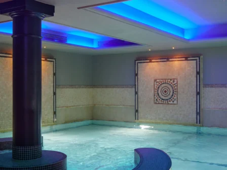 Luxurious indoor hotel pool with ambient lighting, mosaic-tiled walls, and modern design for relaxation and leisure.