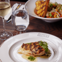 Elegant hotel dining with grilled chicken and wine, showcasing luxurious amenities for a fine dining experience.
