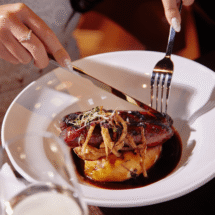 Elegant dining experience with gourmet duck dish and wine at luxury hotel restaurant.