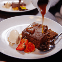 Indulgent chocolate dessert with caramel sauce, fresh strawberries, and ice cream in the hotel's elegant dining room.