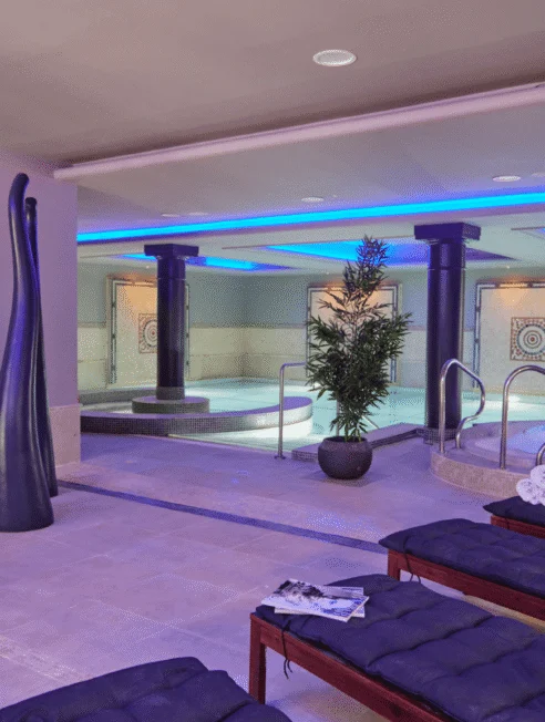 Luxurious indoor spa with jacuzzi, plush loungers, and ambient lighting, perfect for relaxation and rejuvenation.