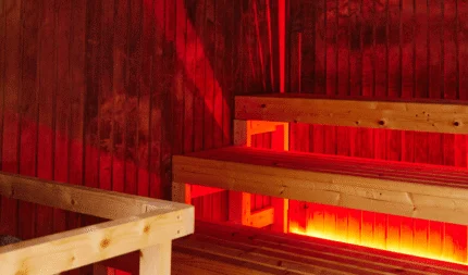 Inviting hotel sauna with warm wooden benches and soothing red light, perfect for relaxation and rejuvenation.
